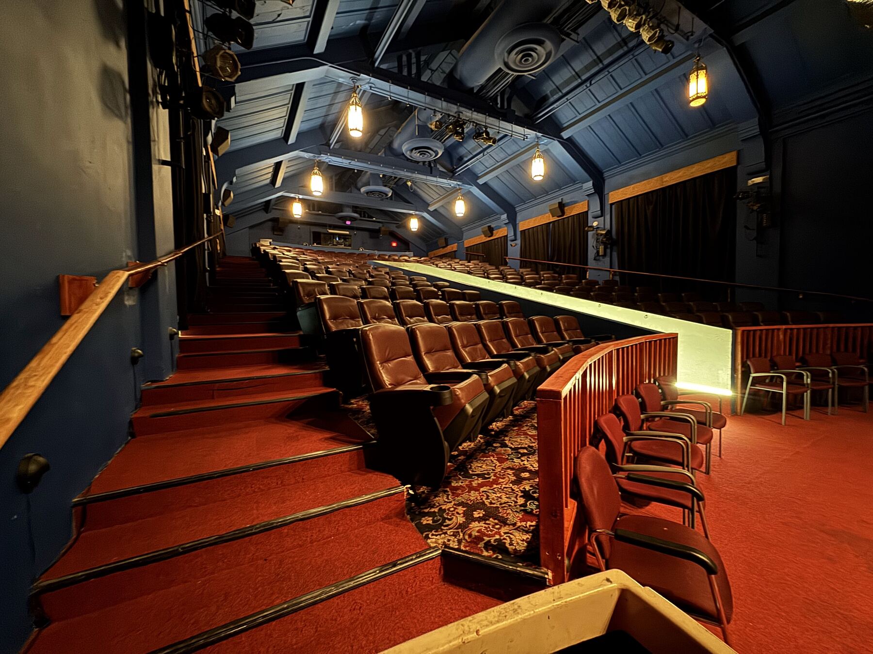 Savor Cinema auditorium: stairs and fabric seating under a blue wood-beam ceiling